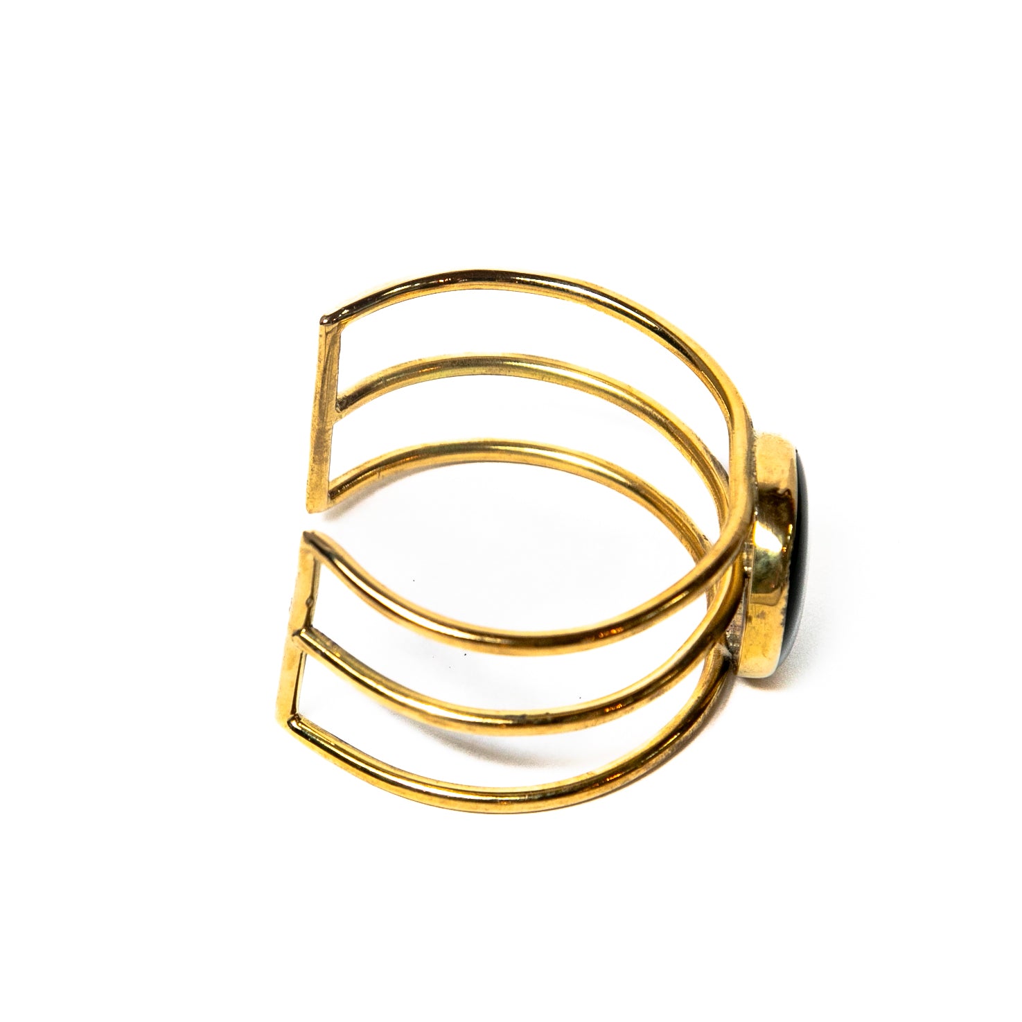 A side view of a beautifully handcrafted gold-toned cuff bracelet with a colorful glass stone in the center. Versatile and easy to wear from day to night.