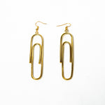 A pair of modern brass earrings featuring a unique paperclip shape. The earrings are sleek and stylish.